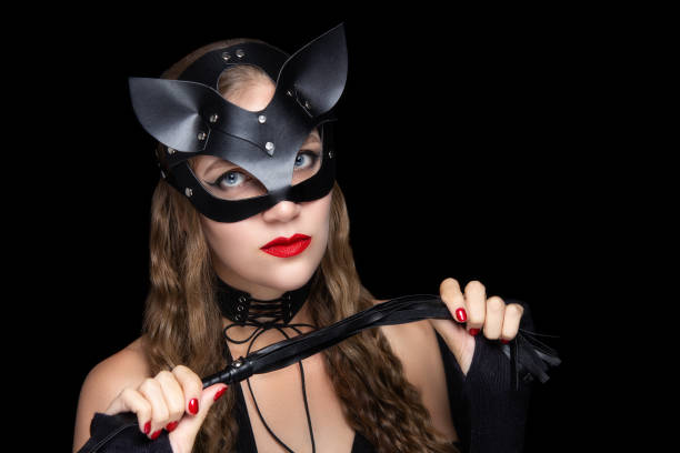 Halloween art make up Woman wearing cat mask, sexual roleplay. Professional make-up bright red lipstick. Subordinate and dominate partner. Ready to Halloween party kitten killer assassin. Holds a whip in her hand to pump dominatrix stock pictures, royalty-free photos & images