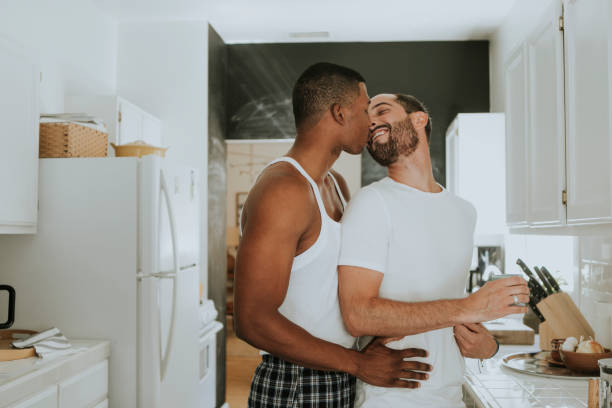 pareja gay abrazos en la cocina - gay man homosexual men kissing fotografías e imágenes de stock