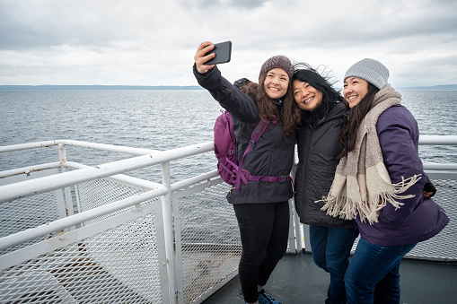 Viaje de invierno en Ferry, madre e hijas adolescentes tomando Selfie photo