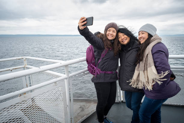 viaje de invierno en ferry, madre e hijas adolescentes tomando selfie - ferry fotografías e imágenes de stock