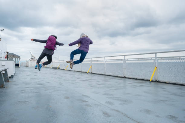 hermanas adolescentes saltando al unísono en la cubierta del ferry, canadá - offbeat fotografías e imágenes de stock