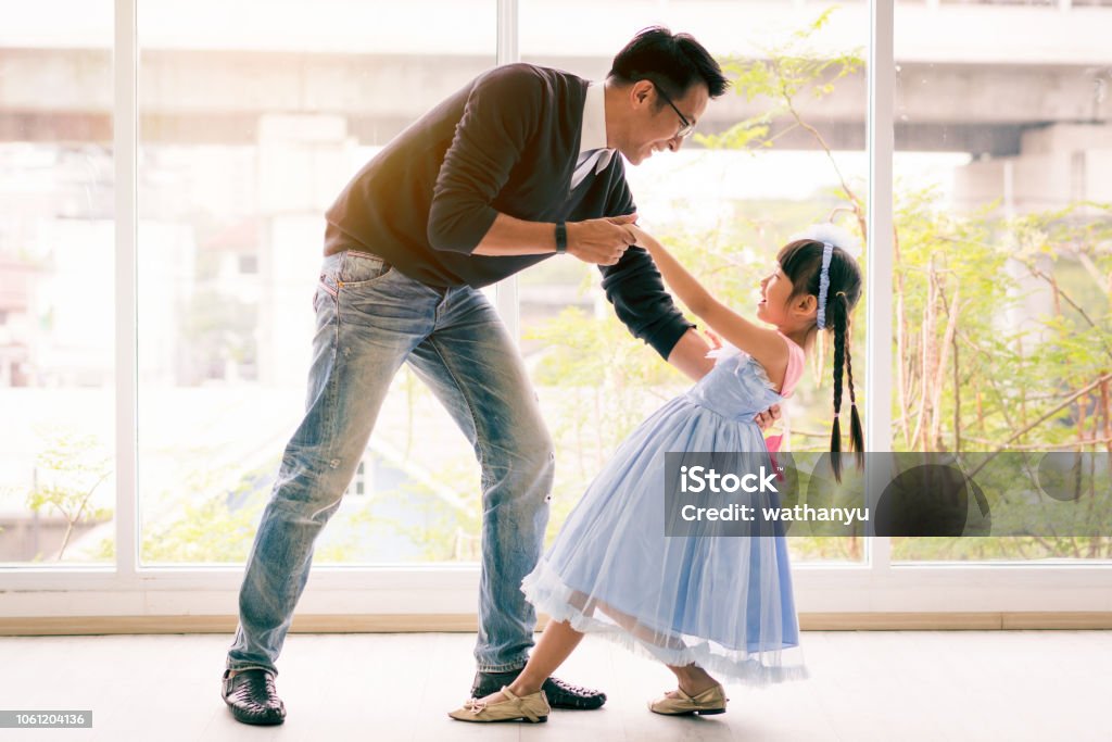 Cute little girl is dancing with her daddy. Having fun at home together concept Father Stock Photo