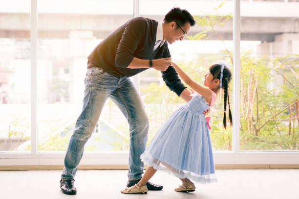 cute little girl is dancing with her daddy. having fun at home together concept - pai e filha a dançar imagens e fotografias de stock