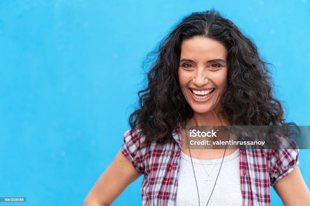 Portrait of smiling mature women on blue background Portrait of smiling brown haired woman on blue background. Senior woman relaxing Women Stock Photo