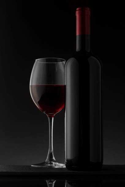 istock Red wine bottle and glass on the black background 1061211268