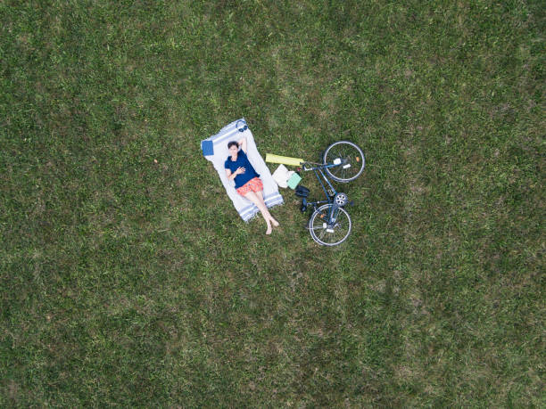 junge frau entspannend in einem öffentlichen park - luftbild - short cycle stock-fotos und bilder