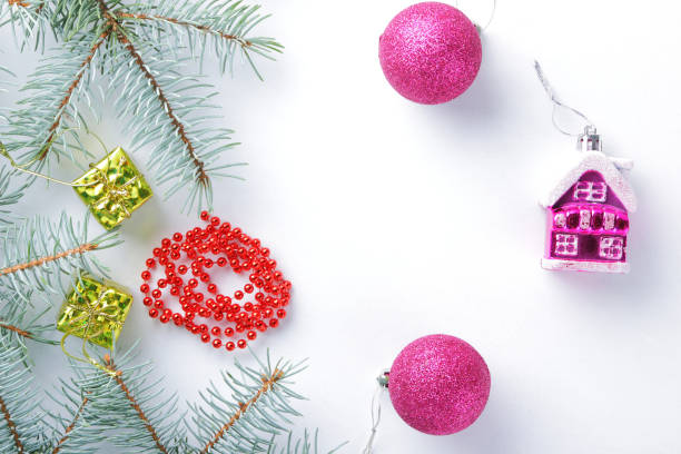 istock Christmas decorations. Spruce branches and holiday decorations on white background. Pink balls and toy house. Red necklace and golden boxes for festive Christmas tree 1061221424