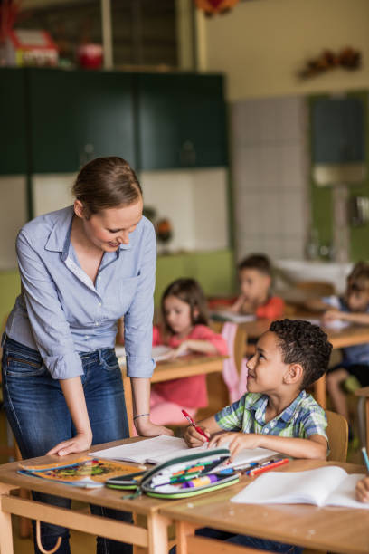 istock Smiling elementary teacher talking to black boy on a class at school. 1061222266