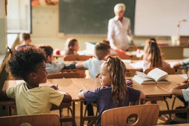 istock Rear view of smiling schoolgirls talking during a class at elementary school. 1061224162