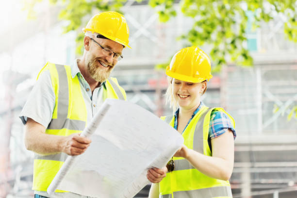istock Male and female construction professionals smiling over blueprints 1061226260