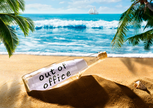 Message in a bottle with the note out of office on a beautiful tropical beach