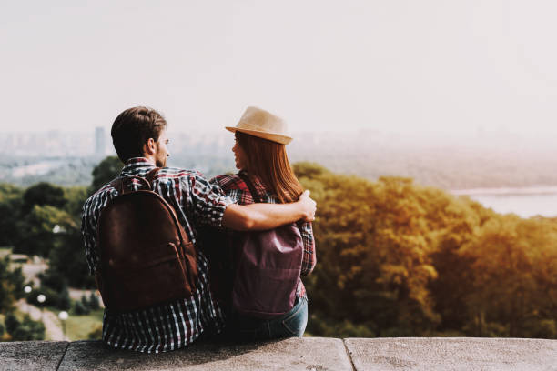 istock Young Couple Sitting on Ledge and Looking at Park 1061230122