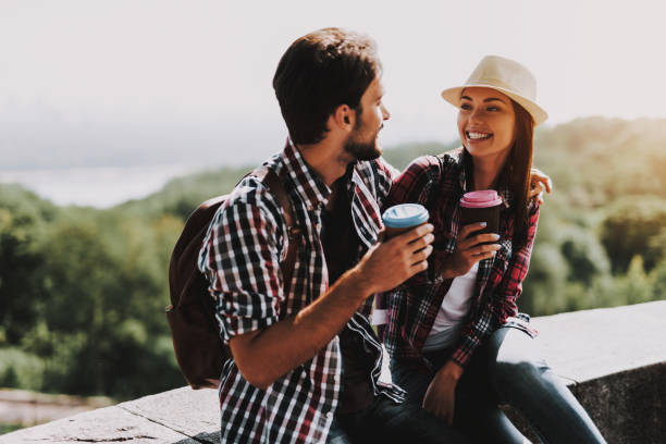 istock Happy Couple Sitting on Ledge and Drinking Coffee 1061230150