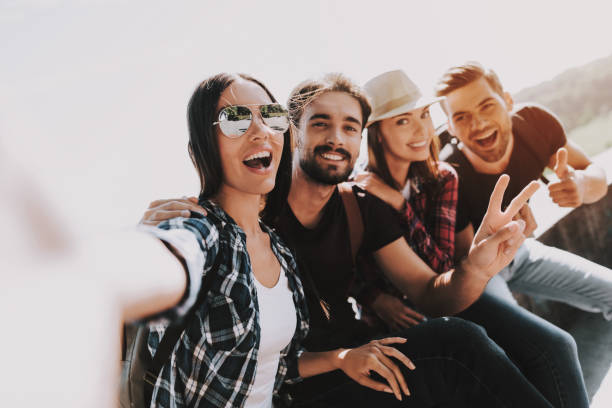 istock Young Smiling People Sitting in Park taking Selfie 1061230250