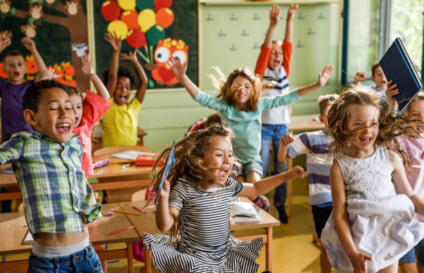 istock Large group of joyful elementary students jumping in the classroom. 1061230292