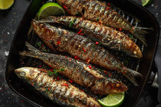 istock Grilled sardines with thyme, chili and lime wedges on cast iron skillet 1061236792