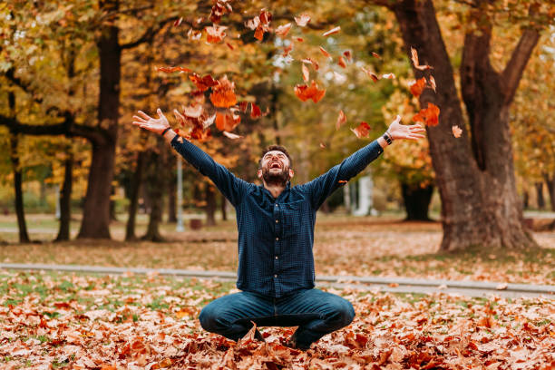 istock Young man throwing autumn leaves in the air 1061239312