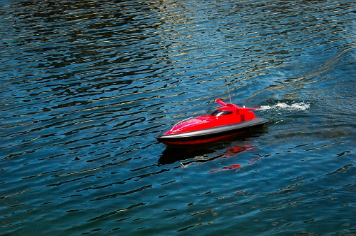 red remote ship toy in river on sunny day with reflection copy space