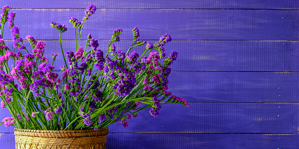 Pink and purple Statice/Limonium or sea-lavender flowers against a violet worn wood panel board background, lots of texture.
