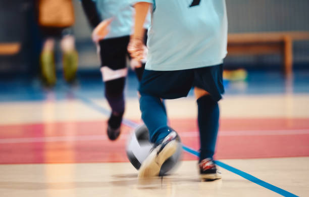 giovani giocatori di futsal e pallone da calcio con sfocatura del movimento. giocatori di calcio a 5 indoor in movimento che giocano a allenamento. palazzetto dello sport indoor. giocatori sportivi che calciano partita. dribbling allenamento futsal - futsal indoors soccer ball soccer foto e immagini stock