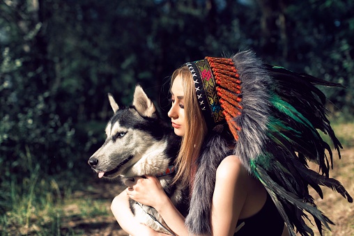 A girl with a dog in an Indian headdress