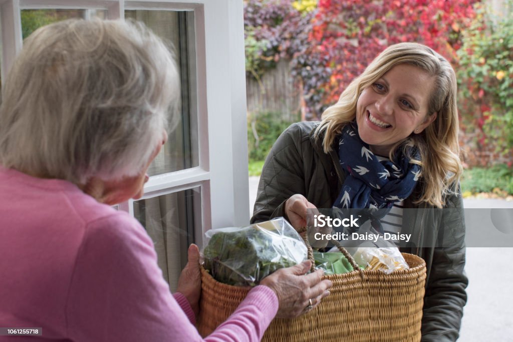 Vicina di casa che aiuta la donna anziana con lo shopping - Foto stock royalty-free di Sostegno morale