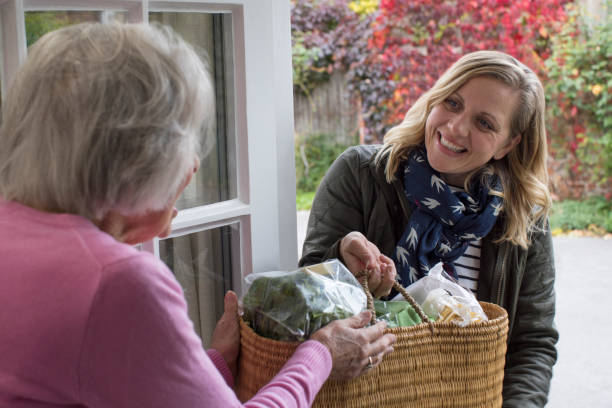 female neighbor helping senior woman with shopping - help imagens e fotografias de stock