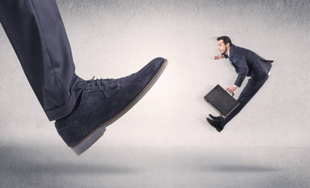 istock Small businessman kicked by big shoe 1061258066