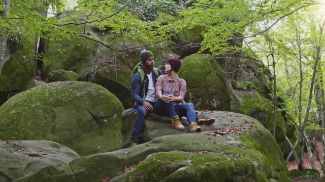 Romantic man and woman sitting on rock in forest