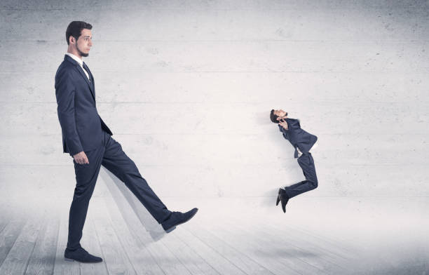istock Big man kicking small man with grungy background 1061259418