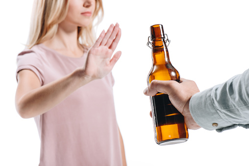 cropped image of blonde woman rejecting bottle of unhealthy beer isolated on white