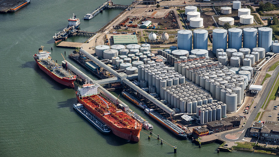 Aerial view of oil tankers moored at an oil storage silo terminal port.