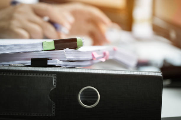 istock Pile of unfinished documents stack paperwork and report files on busy overwork desk with blur businessman hands working for searching information. Business and Accounting planning budget concept 1061283450