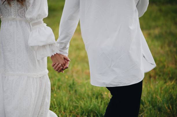 istock Midsection Of Couple Holding Hands While Standing On Grassy Field 1061284890