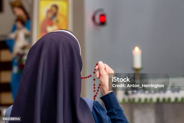 View From Back Of A Religious Sister Holding Rosary And Praying Stock Photo - Download Image Now