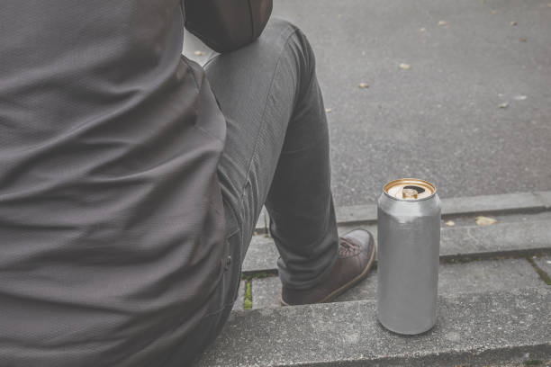 istock Young man with metallic can sitting on stairs. Beer drinking. Suffering from life difficulties or psychological problems. Depressive atmosphere. Dark, gloomy thoughts. Social isolation. Back view. 1061289862