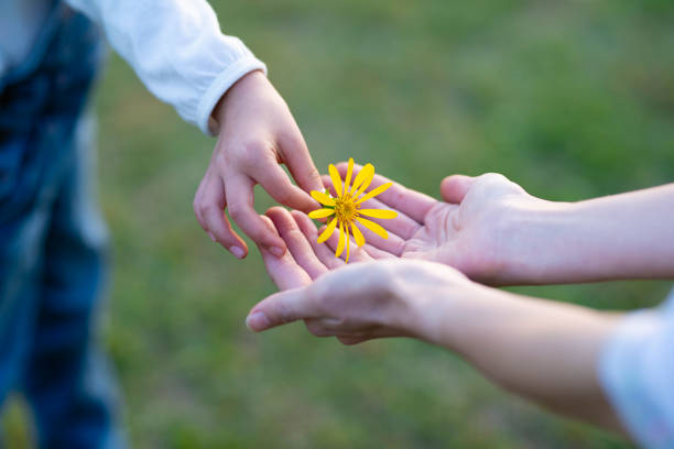 Parent and child handing yellow flower