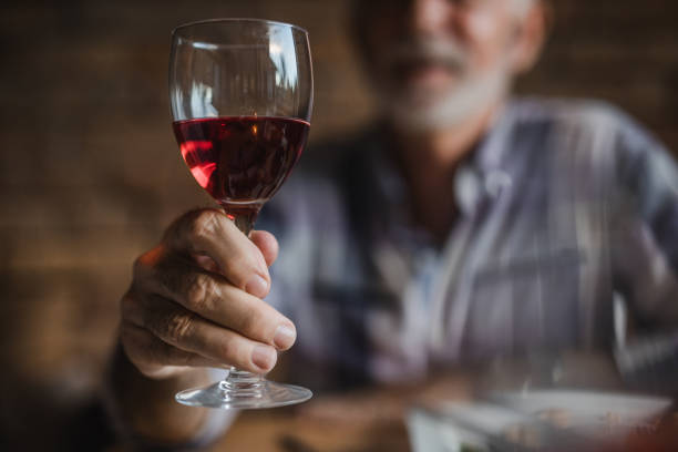 nahaufnahme von unkenntlich senior mann hält glas rotwein. - nur ein mann mittleren alters stock-fotos und bilder