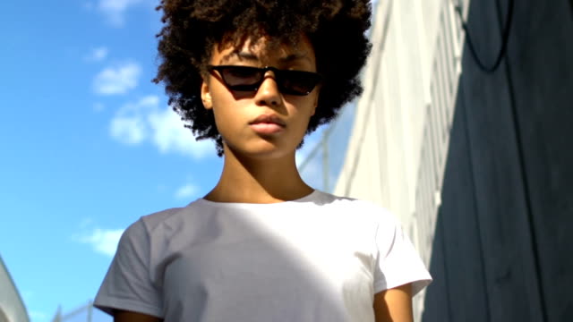 Self-confident woman in dark sunglasses posing for camera, urban style, fashion