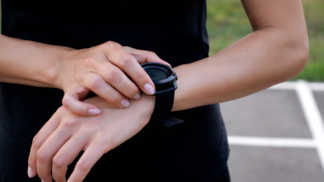 Woman setting up the fitness smartwatch for running. Sporty girl checking watch device, close up.