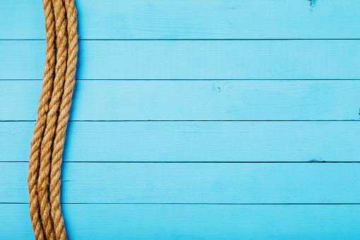 Rope on a wooden board painted blue with copy space, top view
