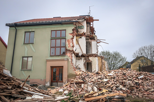 Excavator has demolished half an old residential building. Pile of bricks and scrap.