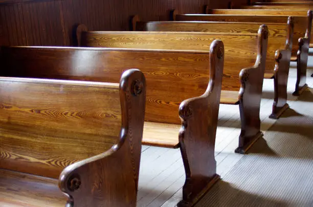 Carved Wooden pews in church in sunshine