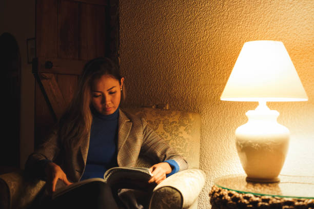istock Woman reading book in hotel lobby at night with low light 1061319150
