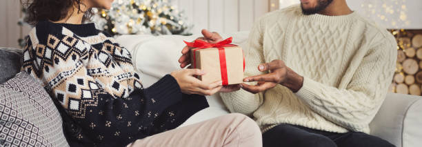 gut aussehender mann überraschend mädchen mit weihnachtsgeschenk - gift new year couple men stock-fotos und bilder