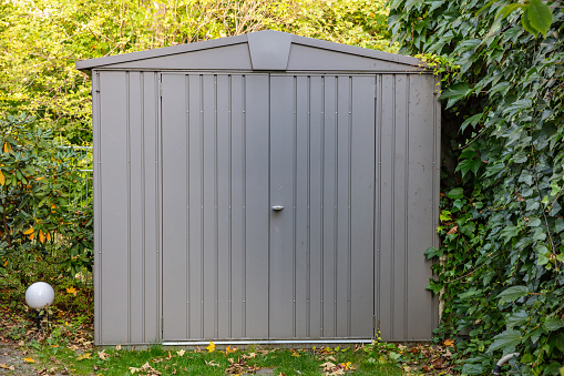 Gardening tools storage shed in the house backyard, autumn nature background