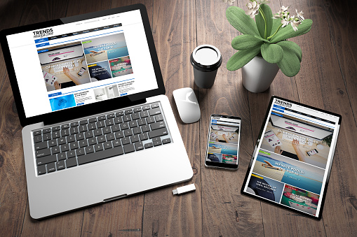 3d rendering of three devices with responsive magazine website on screen on wooden desktop top view