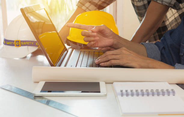 istock Architect engineer using laptop for working with yellow helmet and laptop on table. 1061329726