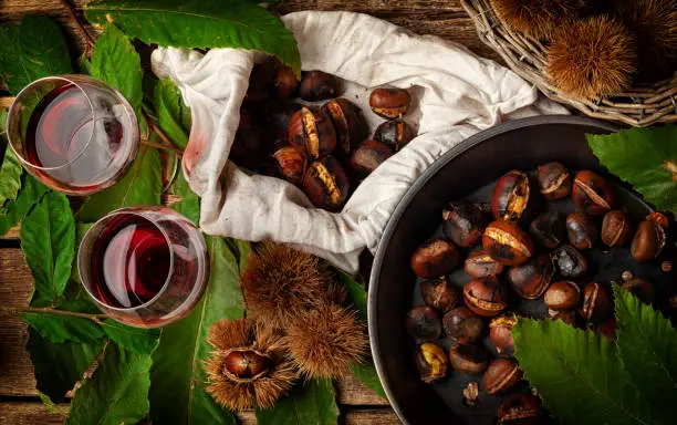 Top view of Roasted chestnuts in iron skillet on wooden table.