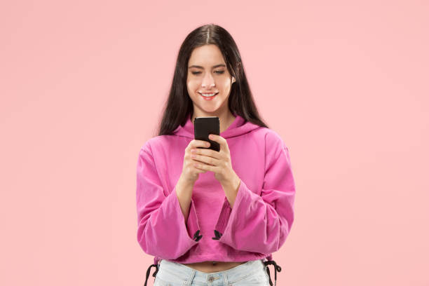 istock Young beautiful woman using mobile phone studio on pink color background 1061345984